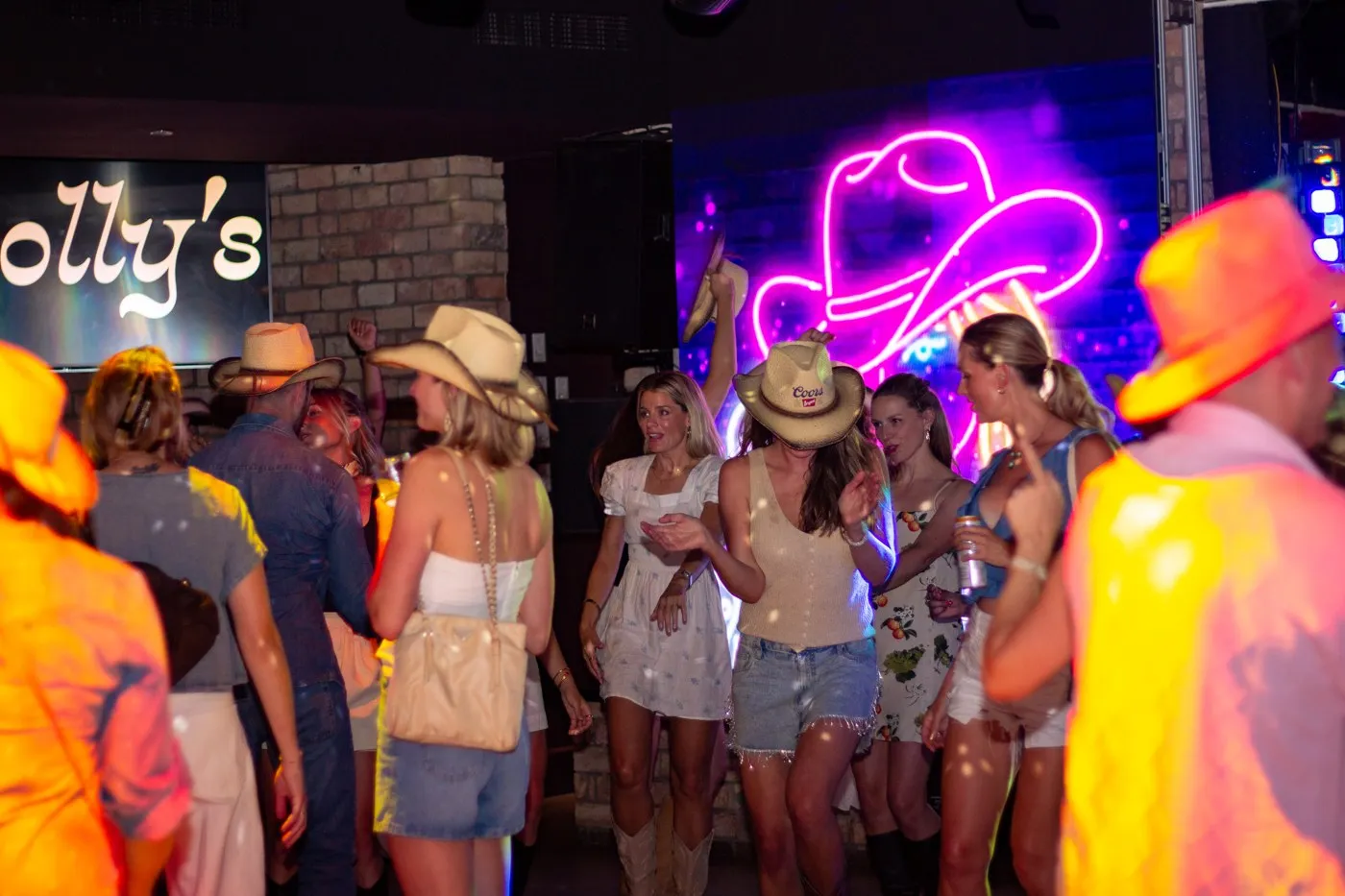 The crowd in cowboy hats under the neon